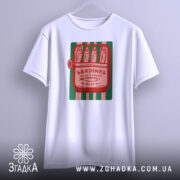 Футболка сардини білого кольору, підвішена на вішалці, з принтом у вигляді консервної банки з сардинами, червоний текст на зеленому фоні, фон світло-сірий.