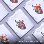 Футболка серце музиканта, біла, зображена з правого ракурсу, на фоні світло-сірого кольору, принт з серцем, що містить музичні інструменти, такі як гітара, труба та клавіші піаніно, виконаний в яскравих кольорах.