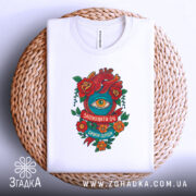 Футболка серце око мотив, складена футболка на плетеній кошику, ракурс зверху, фон світлий, принт з червоним серцем, оком та квітами, напис 'Заплющити очі, бачити серцем'.