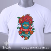 Футболка серце око мотив, складена футболка на білому фоні, ракурс зверху, принт з червоним серцем, оком та квітами, напис 'Заплющити очі, бачити серцем', етикетка з зеленим шнурком.