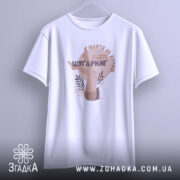 Футболка шугаринг без ілюзій, біла, підвішена на вішалці, фон світло-сірий, принт з зображенням жіночих ніг та текстом у коричневих тонах.