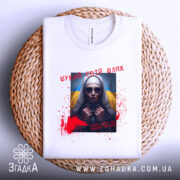 Футболка шукай свій шлях. Біла футболка, складена на плетеній кошику, з принтом на грудях, що зображає жінку в темних окулярах. На фоні видно жовто-блакитний прапор, а також червоні плями, що нагадують кров, та напис українською мовою.