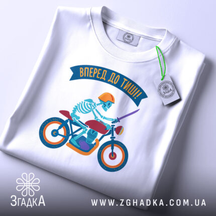 Футболка скелет на мотоциклі, біла, зображена з верхнього ракурсу, фон світло-сірий, принт з скелетом у шоломі на червоному мотоциклі, з зеленим ярликом та написом 'Вперед до тиші!'.