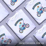 Футболка скелет на мотоциклі, біла, зображена з близького ракурсу, фон світло-сірий, принт з скелетом у шоломі на червоному мотоциклі з синіми колесами та написом 'Вперед до тиші!'.