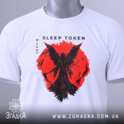Футболка Sleep Token білого кольору, складена на поверхні, з принтом червоного кольору, що зображає фігуру з крилами на фоні червоного кола, видно етикетку з зеленим шнурком, фон світло-сірий.