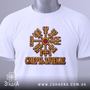 Футболка смерть зачекає, біла, зображена зверху, на фоні світло-сірого градієнту, принт з символом та написом 'СМЕРТЬ ЗАЧЕКАЄСЬ' виконаний в золотистих та червоних кольорах, з зеленим ярликом.