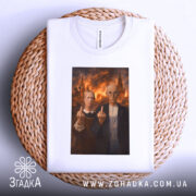 Футболка сміливий політичний принт, біла, складена на плетеній основі, фон світлий, принт з двома персонажами, які показують середні пальці на фоні палаючих будівель.