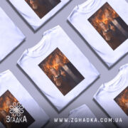 Футболка сміливий політичний принт, біла, зображена на манекені, фон сірий, принт з двома персонажами, які показують середні пальці на фоні палаючих будівель.