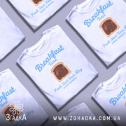 Футболка сніданок новий день, біла, зображена на манекені, фон світло-сірий, принт з написом 'Breakfast Time' та зображенням хліба з шоколадом.