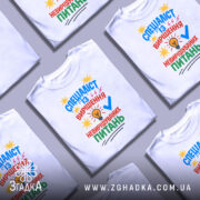 Футболка спеціаліст із питань білого кольору, зображена з фронтального ракурсу на манекені, фон світло-сірий, принт містить яскраві кольори: синій, червоний, жовтий та зелений, текст ілюстрований зображенням лампочки та зірочок.