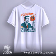 Футболка спілкування з довбойобами, біла, зображена на вішалці, фон світло-сірий, принт з чоловіком у навушниках, який піднімає великий палець, текст червоного та зеленого кольорів.