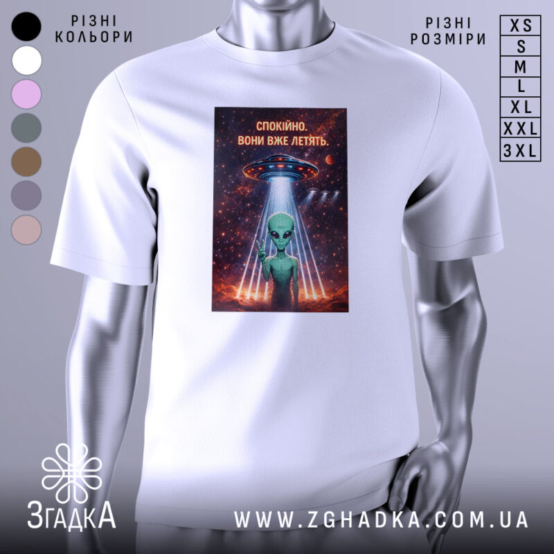 Футболка спокійно вони летять, біла, зображена з правого ракурсу, на фоні градієнтного сірого, принт з зеленим інопланетянином, який показує знак миру, під космічним кораблем, оточеним зірками та планетами.