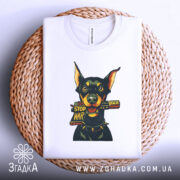 Футболка стоп війна, біла, зображена зверху на плетеній основі, фон нейтральний, принт з доберманом, що тримає табличку 'STOP WAR', видно деталі горловини.