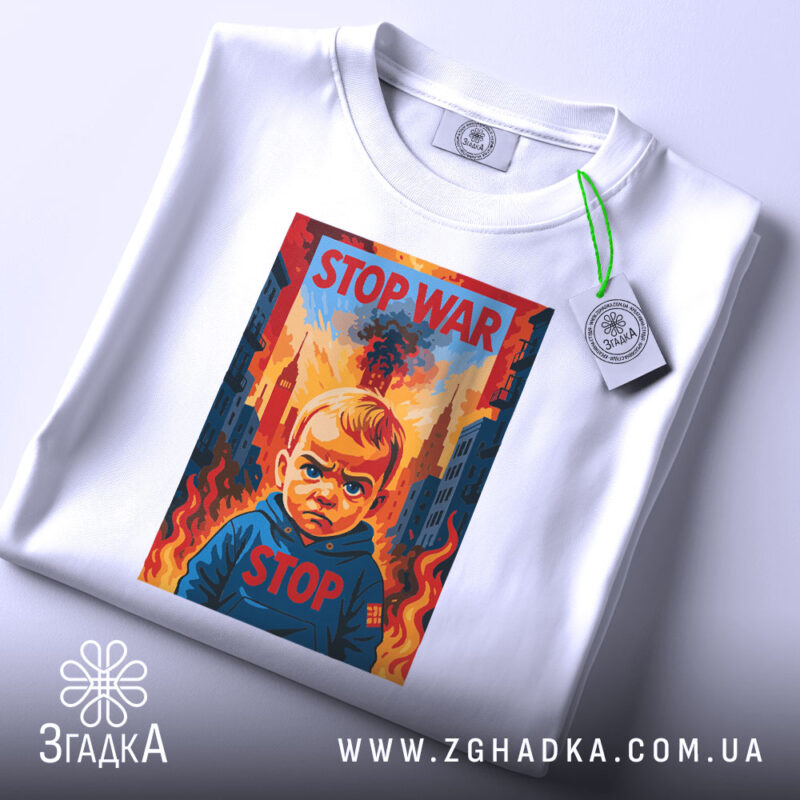 Футболка Stop War арт, біла, складена на поверхні, фон світло-сірий, принт з зображенням дитини з серйозним виразом обличчя, на фоні вогню та будівель, текст "STOP WAR" у верхній частині принта, з етикеткою на комірці.