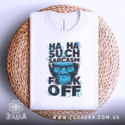 Футболка Such Sarcasm білого кольору, складена на плетеному кошику, фон світло-сірий, принт з зображенням горили та текстом "HA HA SUCH SARCASM F*CK OFF" у чорному та блакитному кольорах.
