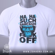 Футболка Such Sarcasm білого кольору, складена на столі, фон світло-сірий, принт з зображенням горили та текстом "HA HA SUCH SARCASM F*CK OFF" у чорному та блакитному кольорах, з біркою на зеленому шнурку.