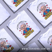 Футболка супер бабуся, біла, зображена на манекені, фон світло-сірий, принт з веселою бабусею в червоному плащі з логотипом супермена та написом 'СУПЕР БАБУСЯ'.