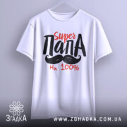 Футболка супер тато білого кольору, підвішена на вішалці, фон світло-сірий, принт з текстом 'Super ПАПА' червоного та чорного кольорів, з малюнком вусів.