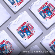 Футболка супер тато, біла, зображена з фронтального ракурсу на манекені, фон нейтральний, принт містить червоний, синій та білий кольори, з зображенням кулака та написом 'SUPER DAD'.