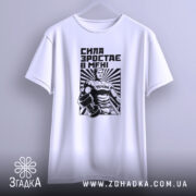 Футболка сила зростає в мені, біла, підвішена на вішалці, фон світлий, принт з чоловіком у спортивному костюмі з гантелями, чорний і білий кольори, текст "СИЛА ЗРОСТАЄ В МЕНІ".