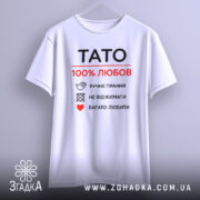 Футболка тато білого кольору, зображена з фронтального ракурсу на вішалці, фон світло-сірий, принт чорного та червоного кольорів з написом 'TATO 100% ЛЮБОВ' та символами догляду за одягом.