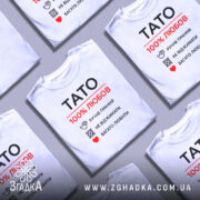 Футболка тато білого кольору, зображена з фронтального ракурсу на манекені, фон світло-сірий, принт чорного та червоного кольорів з написом 'TATO 100% ЛЮБОВ' та символами догляду за одягом.