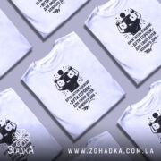 Футболка тато білого кольору, зображена з правого ракурсу на манекені, фон світло-сірий, принт чорного кольору з написом 'БУТИ ТАТОМ ОЗНАЧАЄ БУТИ ГЕРОЄМ ДЛЯ СВОЇХ ДІТЕЙ КОЖНОГО ДНЯ' та зображенням батька з дитиною на плечах.