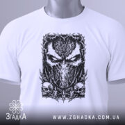 Футболка темна маска, біла, складена на поверхні, з ракурсу зверху, фон світло-сірий, принт з чорним малюнком маски та черепами, на футболці є етикетка з зеленим шнурком.