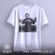 Футболка темний романтик, біла, підвішена на вішалці, з принтом чорного персонажа, що робить жест серця, на фоні автомобіля.