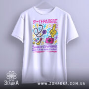 Футболка терапевт білого кольору, зображена на манекені з лівого боку, фон світло-сірий, принт кольоровий, містить малюнки стетоскопа, пальця вказівника, медичної сумки та інших медичних предметів, текст на футболці українською мовою.