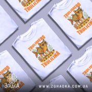 Футболка Trulimero Trulicina білого кольору, зображена на манекені з правого ракурсу, фон світло-сірий, принт з веселим котом у сонцезахисних окулярах і риб'ячим тілом, оточений рослинністю, текст 'TRULIMERO TRULICINA' яскраво-оранжевого кольору.