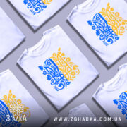 Футболка тризуб український орнамент, біла, зображена з правого ракурсу на манекені, фон світло-сірий, принт у синьо-жовтих тонах з квітковими елементами.