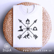 Футболка турист білого кольору, складена на плетеній основі, зображена з верхнього ракурсу, фон світлий, принт чорного кольору з символами активного відпочинку, включаючи компас, вогонь, гори та намет.