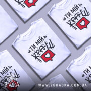 Футболка ти мій краш, білого кольору, зображена з фронтального ракурсу на манекені, фон світло-сірий, принт містить текст "ТИ МІЙ КРАШ" у чорному кольорі та червоний коментар з серцем.