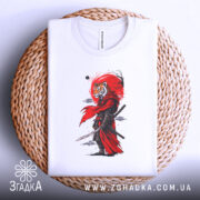 Футболка Тигр самурай воїн, біла, складена на плетеній кошику, фон світло-сірий, принт з тигром у червоному плащі, вид зверху.