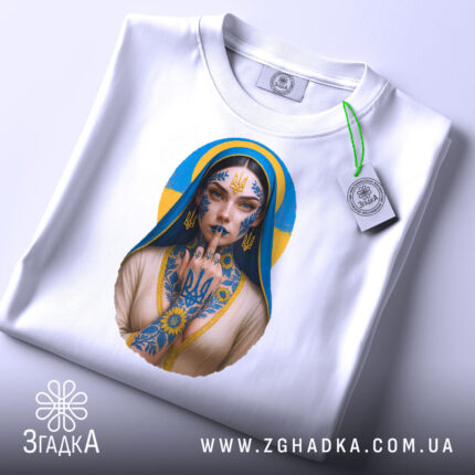 Футболка українська тату, біла, складена на столі, фон світло-сірий, принт з зображенням дівчини з татуюваннями, на футболці є етикетка з зеленим шнурком.