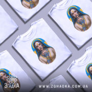 Футболка українська тату, біла, зображена на манекені, фон світло-сірий, принт з зображенням дівчини з татуюваннями, яка тримає палець на губах, з синьо-жовтим фоном.