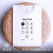 Футболка unlock me, білого кольору, складена на плетеній кошику, фон світло-сірий, принт з клавіатурою та написом 'UNLOCK ME' чорного кольору.