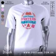 Футболка вчитель у світі білого кольору, зображена на манекені з правого боку, фон світло-сірий, принт містить текст 'НАЙКРАЩИЙ ВЧИТЕЛЬ У СВІТІ' у рожевих та блакитних тонах, оточений елементами, такими як книга, дзвоник та ручка.