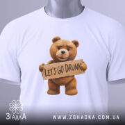 Футболка ведмедик let’s drunk, біла, складена на столі, фон світло-сірий, принт з ведмедиком, який тримає табличку з написом 'LET'S GO DRUNK', на комірці є етикетка.