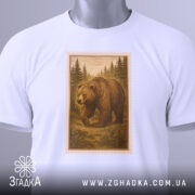 Футболка ведмідь білого кольору, складена на поверхні, з видимим етикеткою. Принт з ведмедем в лісі в коричневих відтінках, обрамлений рамкою, що нагадує поштову марку, на фоні світло-сірого градієнту.