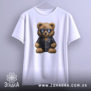 Футболка ведмідь патріот, біла, підвішена на вішалці, фон світло-сірий, принт ведмедя в чорній куртці та сонцезахисних окулярах з тризубом.