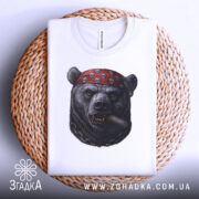 Футболка ведмідь з сигарою, біла, складена на плетеній основі, зображення ведмедя в червоній бандані з черепами, ракурс зверху, фон світлий, деталі принта чіткі.