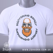 Футболка відпускаю бороду, білого кольору, лежить на плоскій поверхні, фон світло-сірий, принт з усміхненим бородатим чоловіком у сонцезахисних окулярах, на футболці є етикетка з зеленим шнурком.