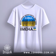 Футболка Війна це імена. Біла футболка з коротким рукавом, підвішена на вішалці. Принт з текстом 'ВІЙНА' та силуетами людей на фоні жовто-блакитного прапора. Фон світло-сірий, простий.