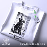 Футболка воля починається з мене. Біла футболка з коротким рукавом, зображена з верхнього ракурсу на фоні світлого кольору. На футболці чорний принт з зображенням чоловіка в одязі 19 століття, а також видна етикетка з зеленим шнурком. Текст під зображенням: 'ВОЛЯ ПОЧИНАЄТЬСЯ З МЕНЕ'.