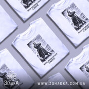 Футболка воля починається з мене. Біла футболка з коротким рукавом, зображена з фронтального ракурсу на манекені. На футболці чорний принт з зображенням чоловіка в одязі 19 століття, що стоїть на фоні пейзажу. Текст під зображенням: 'ВОЛЯ ПОЧИНАЄТЬСЯ З МЕНЕ'.