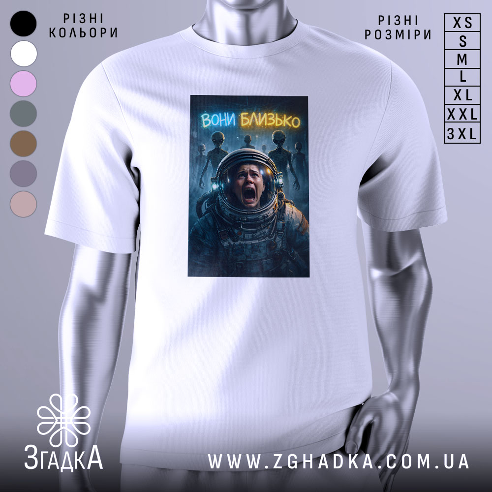 Futbolka Vony Blyzko Koly Kosmos Dyvytsia Na Tebe 1 Футболка вони близько, біла, зображена на манекені, фон світло-сірий, принт з космонавтом, який кричить, на фоні силуети прибульців і написом 'вони близько'.