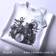 Футболка восьминіг на барабанах, біла, складена на поверхні, фон світло-сірий, принт з восьминогом на барабанах, деталі принта чіткі, на футболці є етикетка з зеленим шнурком.