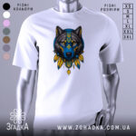 Футболка вовк білого кольору, зображена на манекені, з принтом вовка в синіх та жовтих тонах, фон світло-сірий, деталі принта включають тризуб та пір'я.